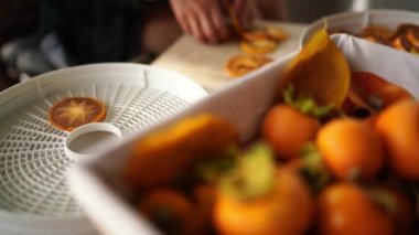 Cook puts pieces of persimmon on a tray for drying fruit near the basket on the table. High quality 4k footage