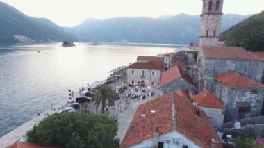 Guests sit at laid tables in the courtyard of the church on the pier. Drone. High quality 4k footage