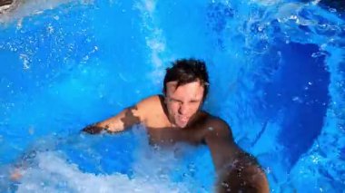 Young man jumps into the pool backwards and sinks to the bottom surrounded by bubbles. High quality FullHD footage