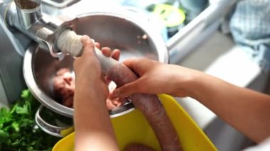 Cook adjusts the sausage casing while filling it with minced meat from a meat grinder. High quality 4k footage