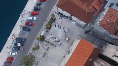 Guests sit at tables near an old house on the Perast embankment. Top view. High quality 4k footage
