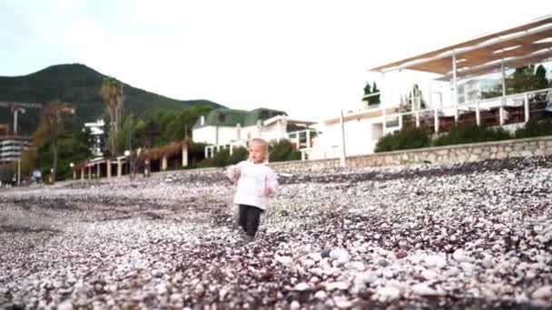 Ragazzina Giacca Cammina Lungo Una Spiaggia Ciottoli Cade Ginocchio Filmati — Video Stock