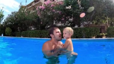 Dad bathes with a little girl in the pool, kissing her and playing. High quality 4k footage