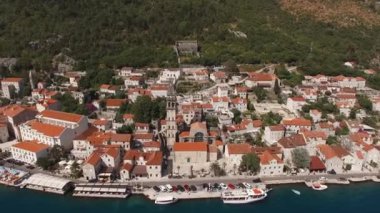 High bell tower of the church of St. Nicholas in Perast among the old houses. Aerial view. High quality 4k footage