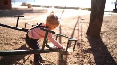 Little girl pours sand on a swing-balancer and wipes it. High quality 4k footage