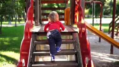 Little girl climbs the steps of a slide at the playground in the park. High quality 4k footage