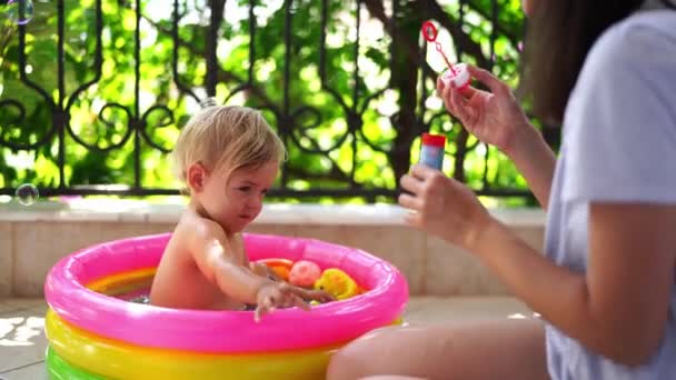 Mam Blaast Zeepbellen Een Klein Meisje Een Opblaasbaar Zwembad Hoge — Stockvideo