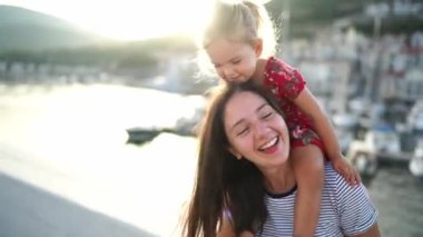 Gülümseyen anne, omuzlarında küçük bir kızla dağların arka planında iskelede dans ediyor. Portre. Yüksek kalite 4k görüntü