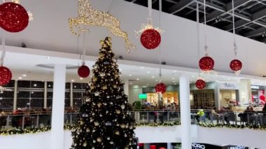 Toplar ve çelenklerle süslenmiş Noel ağacı katlar arasında bir alışveriş merkezinde duruyor. Yüksek kalite 4k görüntü