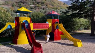 Küçük kız oyun parkında oyuncak kale şeklinde bir kaydırağın etrafında koşuyor. Yüksek kalite 4k görüntü
