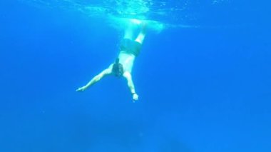 Yüzücü suyun altında yüzer ve dağların arka planına karşı denizin yüzeyine çıkar. Yüksek kalite 4k görüntü