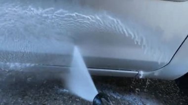 Araba yıkama makinesi arabanın kapısını hortumla yıkıyor. Yüksek kalite 4k görüntü