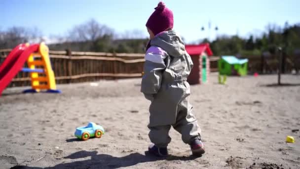 小さな女の子は遊び場のおもちゃの車にシャベルで砂を注ぐ 高品質4K映像 — ストック動画
