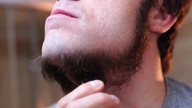 Genç adam jiletle boynunu ve çenesini tıraş ediyor. Yüksek kalite 4k görüntü