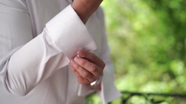 Beyaz gömlekli bir adam kol düğmelerini koluna takıyor. Yakın plan. Yüksek kaliteli FullHD görüntüler