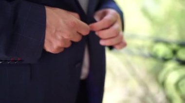 Damat ceketinin düğmelerini bağlıyor, balkonda duruyor. Yakın plan. Yüksek kaliteli FullHD görüntüler