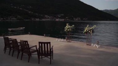 Çiçek buketlerinin yarı kemeri iskemlelerin yanındaki iskelede duruyor. Yüksek kaliteli FullHD görüntüler