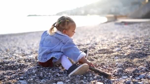 Bambina Siede Una Spiaggia Ciottoli Gioca Con Bastone Piccoli Ciottoli — Video Stock