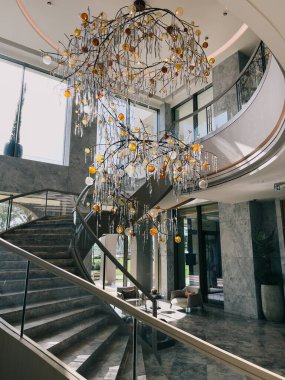 Otelin zeminleri arasındaki merdivenlerin yanındaki tavandan sarkan büyük bükülmüş avize. Yüksek kalite fotoğraf