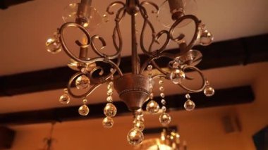 Tavanda kristal kolyeli bronz bir avize asılı. Yüksek kalite 4k görüntü