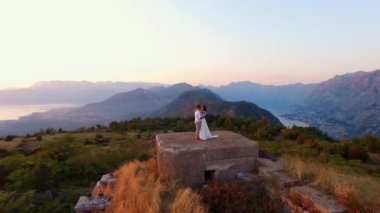 Gelin ve damat, Kotor Körfezi 'nin yukarısındaki Gorazda kalesinin tepesinde birbirlerine sarılıyorlar. Karadağ. Yüksek kalite 4k görüntü