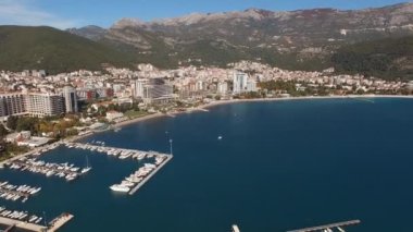 Budva 'nın modern kesimine insansız hava aracı manzarası ve dağların arka planına karşı bir marina. Yüksek kalite 4k görüntü