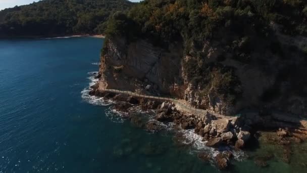 海の波が捨てられた道路で山のふもとに岩に対してクラッシュします 高品質4K映像 — ストック動画