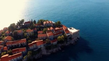 Ağaçlarla çevrili eski binaların insansız hava aracı görüntüsü. Sveti Stefan adası. Karadağ. Yüksek kalite 4k görüntü