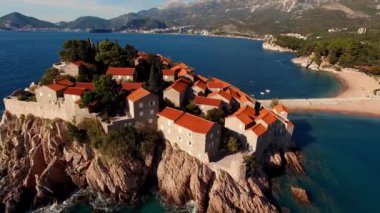 Kayalık ada Sveti Stefan 'da kırmızı kiremitli çatıları olan eski evler. Karadağ. Yüksek kalite 4k görüntü