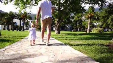 Babam ve küçük bir kız parkta el ele tutuşarak yürüyor. Yüksek kaliteli FullHD görüntüler