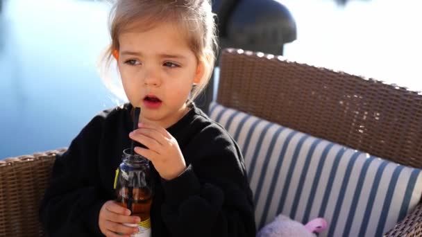 Das Kleine Mädchen Sitzt Auf Einem Korbstuhl Und Trinkt Tee — Stockvideo