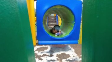 Yumuşak tavşanlı küçük bir kız oyun parkında bir boruya tırmanır. Yüksek kalite 4k görüntü