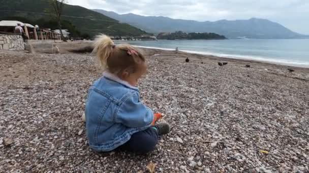 Mała Dziewczynka Siedzi Żwirowej Plaży Wytrząsa Kamyki Swoich Butów Wysokiej — Wideo stockowe