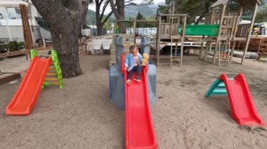 Oyuncak ayılı küçük bir kız oyun parkında kayıyor. Yüksek kalite 4k görüntü