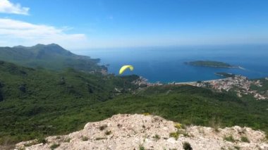 Paraglider körfezin üstündeki dağlarda yeşil ağaçların üzerinden uçuyor. Yüksek kalite 4k görüntü