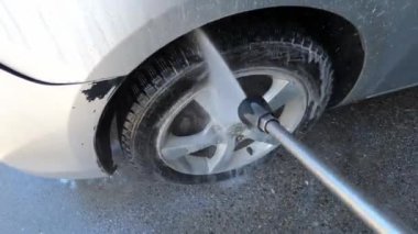 Basınç altında arabanın çarklarını ve kapılarını sabunlu suyla yıkamak. Yüksek kalite 4k görüntü