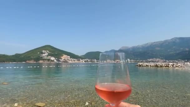 Manusia Mengangkat Gelas Anggur Terhadap Latar Belakang Pantai Dan Gunung — Stok Video