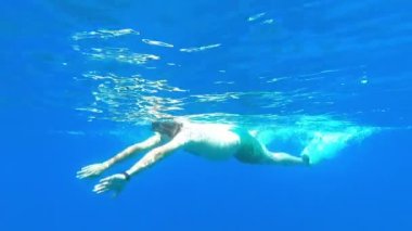 Yüzgeçli bir yüzücü ve şnorkeli olan bir maske mavi denizde suyun altında yüzer. Yüksek kalite 4k görüntü