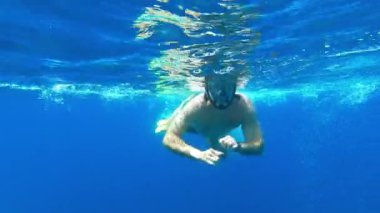 Maskeli bir yüzücü su altında yüzer, elleriyle kürek çeker. Yüksek kalite 4k görüntü