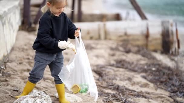 Een Meisje Met Handschoenen Verzamelt Afval Een Zak Het Strand — Stockvideo