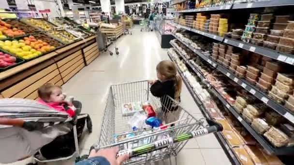 Kleines Mädchen Reitet Einkaufswagen Springt Und Rennt Zwischen Den Gängen — Stockvideo