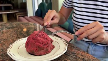 Kız, pembe bir Fransız pastası choux 'sunu craquelin hamuruyla kesiyor. Yüksek kalite 4k görüntü