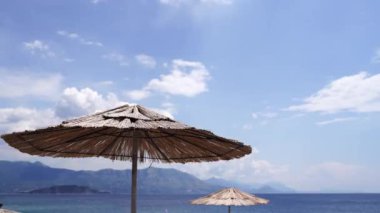 Saman güneş şemsiyeleri deniz kenarında rüzgarda sallanıyor. Yüksek kalite 4k görüntü