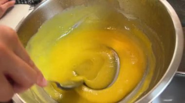 Ev hanımı kaşıkla yumurta sarısını kasede karıştırıyor. Yüksek kalite 4k görüntü