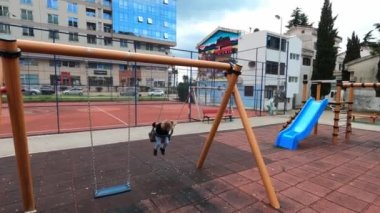Küçük kız parkta zincirli salıncakta sallanıyor. Ağır çekim. Yüksek kalite 4k görüntü