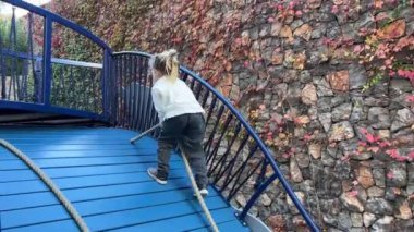 Küçük kız bir halata tutunarak kayıyor ve aşağı kayıyor. Yüksek kalite 4k görüntü