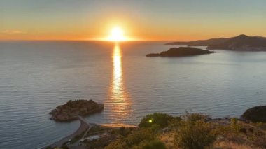 Kotor Körfezi 'ndeki Sveti Stefan adası turuncu günbatımının ışınlarında. Yüksek kalite 4k görüntü