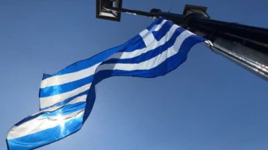 Güneş, fenerin üzerinde rüzgarda dalgalanan Yunanistan bayrağında parlıyor. Yüksek kalite 4k görüntü