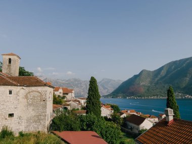 Yeşil ağaçların arasında kırmızı kiremitli çatıları olan eski taş evler. Perast, Karadağ. Yüksek kalite fotoğraf