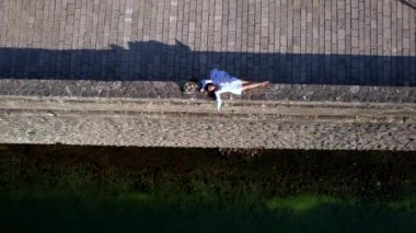 Elinde buket olan gelin, eski kasabanın taş köprüsünün çitlerinde yatıyor. Drone. Yüksek kalite 4k görüntü